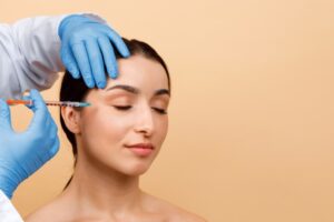 Cosmetologist Doctor Making Botox Injection For Eyes Area To Young Indian Woman